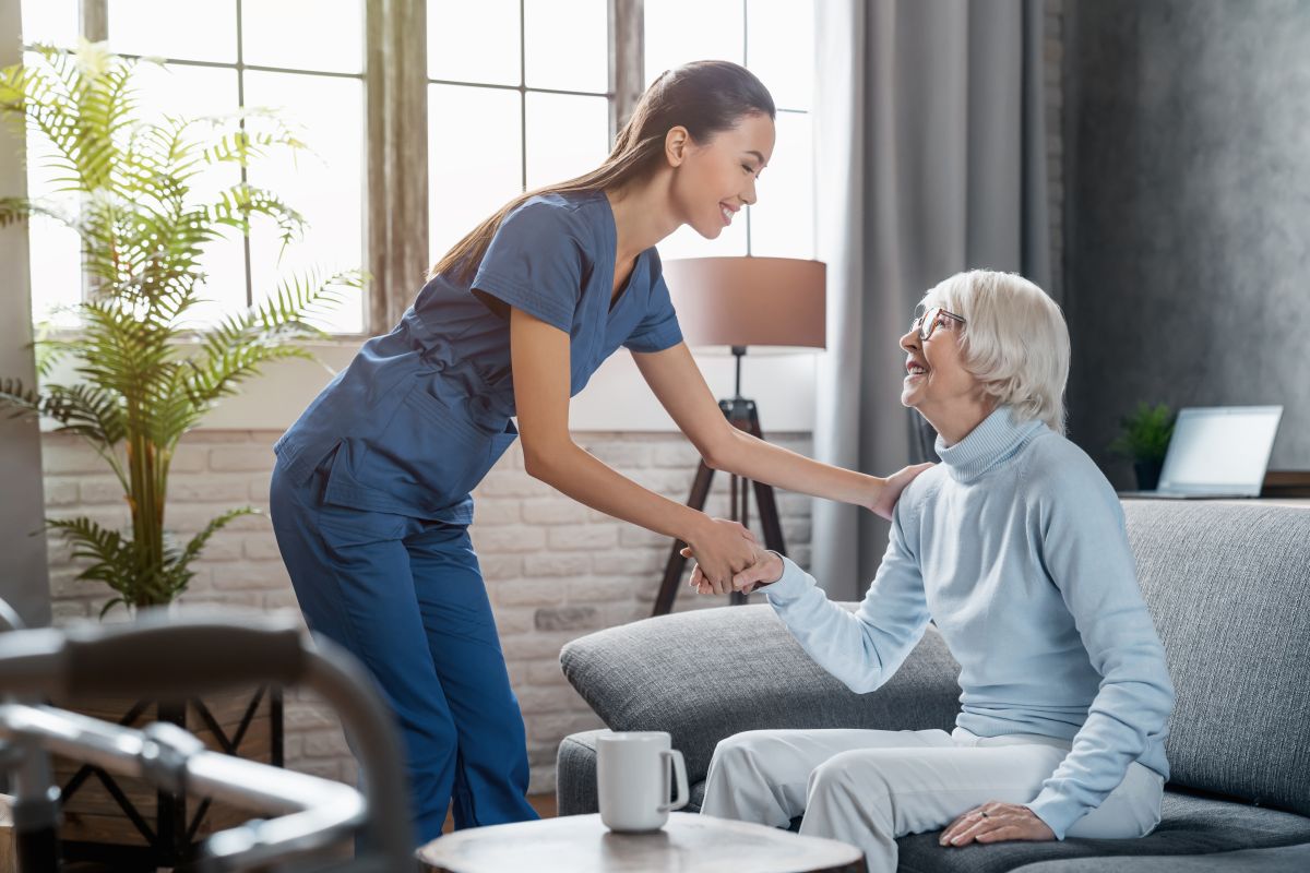 Nurse assists elderly resident in a nursing home lounge