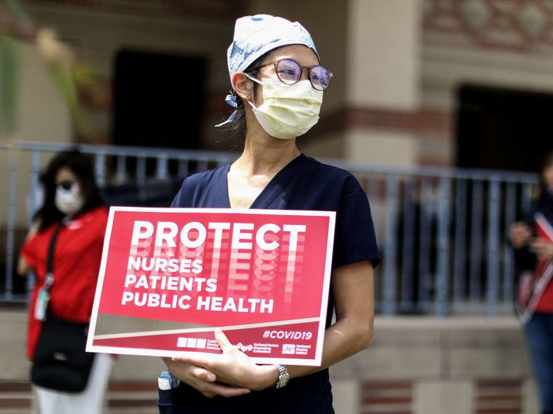 Frontline healthcare worker holding a protest sign