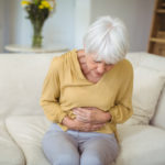 Elderly woman wincing at stomach pain.