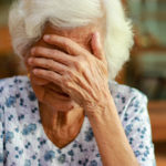 Elderly woman sitting in shame. How caregivers hide their abusive tendencies.