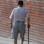 Elderly man with cane wandering the city.